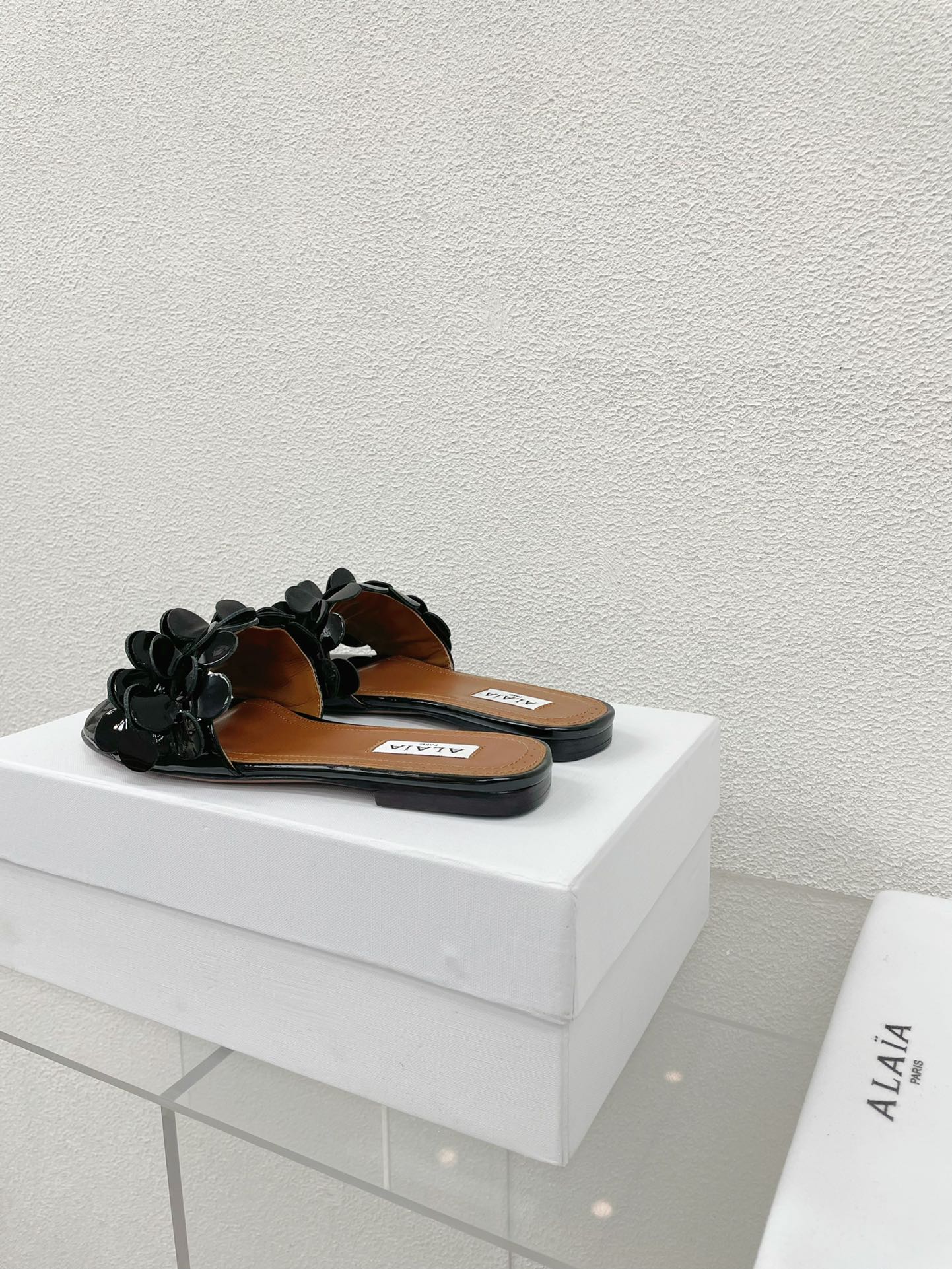 ALAIA FLAT MULE IN BLACK GLOSSY LAMBSKIN