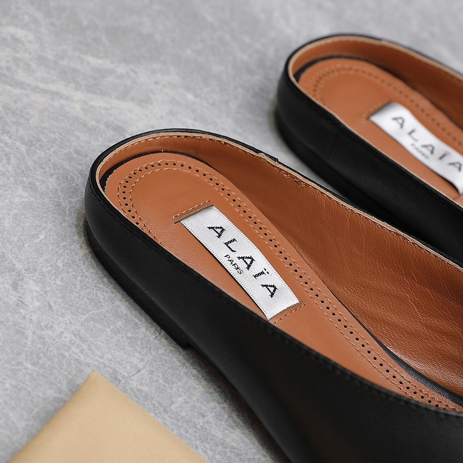 ALAIA FLAT MULE IN BLACK LAMBSKIN